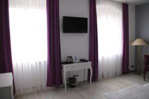 a bedroom with white curtains and a tv on a wall at Hotel Am Markt in Oebisfelde