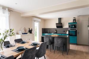 eine Küche mit blauen Schränken sowie einem Tisch und Stühlen in der Unterkunft Chez Lisette - Maison climatisée dans Cancale in Cancale + 10 Fotos