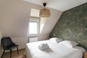 ein Schlafzimmer mit einem großen weißen Bett und einem Stuhl in der Unterkunft Chez Lisette - Maison climatisée dans Cancale in Cancale