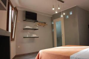 a bedroom with a bed and a tv on the wall at Osa rooms in Bosa