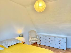 1 dormitorio con 1 cama amarilla y 1 silla en Maison lumineuse - Vue sur l'anse, en La Forêt-Fouesnant