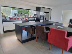 a kitchen with a black counter and red chairs at Fazenda de Jehne in Camamu