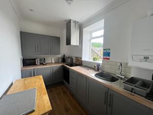 a kitchen with gray cabinets and a sink and a window at The Nest at Alnwick in Alnwick