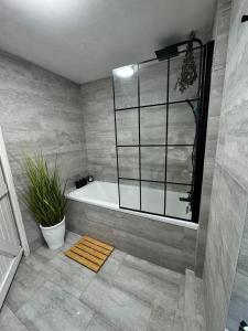 a bathroom with a tub and a plant at Cosy Cottage 7 mins from Cardiff City Center in Cardiff