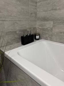 a white bath tub in a bathroom with a tile wall at Cosy Cottage 7 mins from Cardiff City Center in Cardiff +20 photos