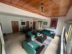 a living room with green couches and a table at Trout Lodges Naran in Naran