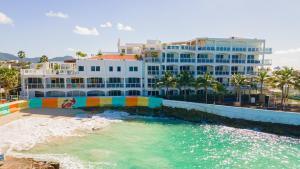 un grand bâtiment blanc avec une piscine à côté d'une plage dans l'établissement Ocean View Studio at Maho Beach, à Maho Reef