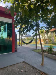 a tree with a hammock in front of a building at Casa com Piscina na Represa de Carlópolis in Carlópolis