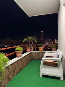 balcón con 2 sillas y suelo verde en Hanna Apartment, en Tirana