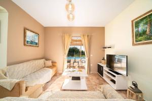 a living room with a couch and a tv at Villa Zeus Skala by Villa Plus in Mavráta