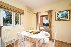 a white dining room with a white table and chairs at Villa Zeus Skala by Villa Plus in Mavráta