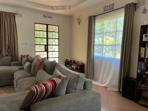 a living room with a couch and two windows at Sinana country Home-Backpackers Stay in Kibongoto