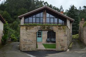 ein kleines Gebäude mit Balkon darüber in der Unterkunft La Casa de Piedra in Herrera de Ibio