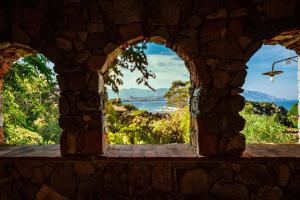 an archway in a stone wall with a view of the ocean at Arbatax Park Resort - Borgo Cala Moresca by Falkensteiner in Àrbatax