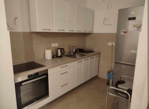 Una cocina con gabinetes blancos y un refrigerador de acero inoxidable. en Room in a nice sunny apartment, en Vračar (historical) 4 fotos más