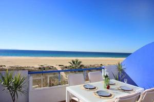 Biały stół z krzesłami i widokiem na plażę w obiekcie Livingtarifa Apartamento Paradise w mieście Tarifa