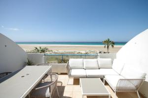 balkon z białymi krzesłami i widokiem na plażę w obiekcie Livingtarifa Apartamento Paradise w mieście Tarifa