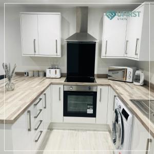 Una cocina con gabinetes blancos y un horno de estufa. en Tastefully decorated 4 Bed Home in Gedling - Near Colwick Country Park, Victoria Retail Park, City Centre & Nottingham Racecourse, en Nottingham
