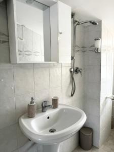 a white bathroom with a sink and a mirror at Residenza Dartuffo - Apartment - City Centre in Scilla