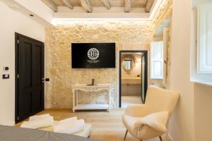 a living room with a fireplace and a television on a wall at Pedra Bianca Luxury Rooms in Cagliari