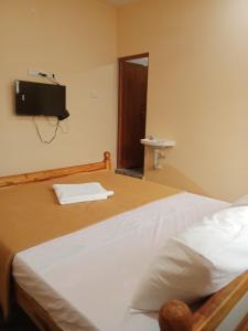 a bedroom with a bed with a tv on the wall at LJ Rooms in Pākkam