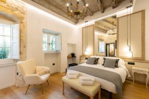 a bedroom with a large bed and two chairs at Pedra Bianca Luxury Rooms in Cagliari