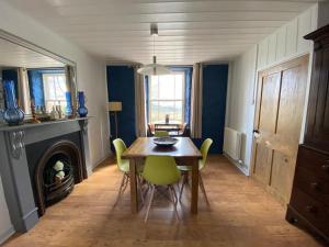 a dining room with a table and chairs and a fireplace at Secluded farmhouse with views in Cwrt-newydd