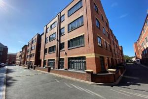 een groot bakstenen gebouw aan de kant van een straat bij Luxury 1-Bed Apartment in JQ, Sleeps 3, Parking & Netflix, Ideal for contractors in Birmingham