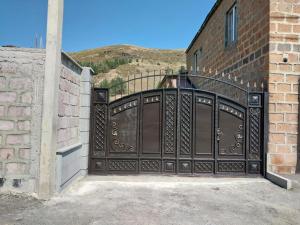 a black metal gate with a brick building at TomHouse in Tsaghkadzor