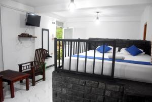 una camera da letto con un letto con cuscini blu e una sedia di Tunnel Side Hotel Ramboda a Ramboda