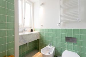 une salle de bain carrelée verte avec un lavabo et des toilettes dans l'établissement Baixa Luxury Penthouse - Stunning Downtown Views, à Lisbonne 22 autres photos