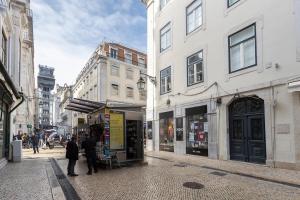 Un groupe de personnes marchant dans une rue avec des bâtiments dans l'établissement Baixa Luxury Penthouse - Stunning Downtown Views, à Lisbonne