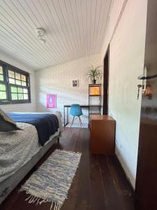 a bedroom with a bed and a table with a blue chair at O Maior hostel da Lagoa in Florianópolis