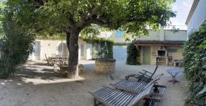 a group of park benches sitting under a tree at Maison de village en Provence in Mouriès
