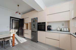 a kitchen with white cabinets and a table at Luxury Apartment in Râmnicu Vâlcea