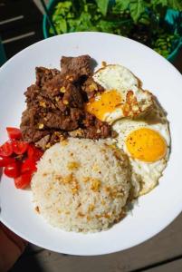 a plate of food with rice and eggs and meat at Laly's B8 cozy Vacation Townhouse in Olongapo
