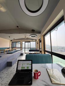 a laptop sitting on a table in a room with windows at Shalom Backpackers Rishikesh in Rishīkesh