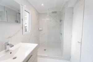 Un baño blanco con ducha y lavabo. en Cozy apartement in the heart of Brussels, en Bruselas