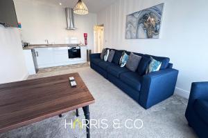 a living room with a blue couch and a table at New Sandpiper Apartments in Fleetwood