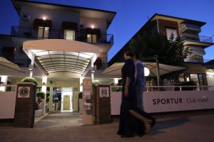 una mujer caminando delante de un edificio en Sportur Club Hotel, en Cervia