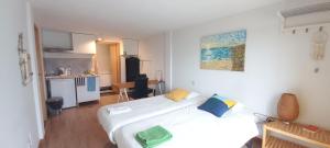 a bedroom with a large white bed and a kitchen at Oporto SurfLodge in Cortegaça