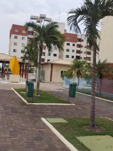 two palm trees and two trash cans in a parking lot at Apartamento Condominio Caminho dos Ventos in Aracaju