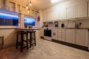 a kitchen with white cabinets and a island with stools at Abisko Panorama House in Abisko +17 photos