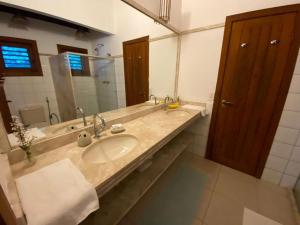 une salle de bain avec un lavabo et un grand miroir dans l'établissement Casa Exclusiva na Falésia - Barraca da Maré, Arraial d'Ajuda, à Arraial d'Ajuda 20 autres photos