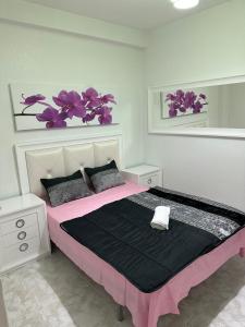 Un dormitorio con una cama rosa con flores púrpuras en la pared en Apartament Luxor, en Linares