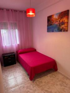 Un pequeño dormitorio con una cama roja en una habitación en Apartament Luxor, en Linares