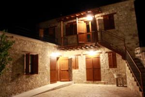 a stone building with wooden doors and stairs at night at Marmaras in Lyso