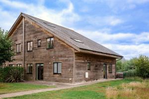 eine alte Holzscheune mit einem Walmdach in der Unterkunft Ardross Lodge in South Cerney