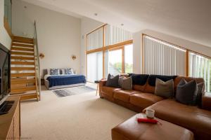 ein Wohnzimmer mit einem braunen Sofa und einigen Fenstern in der Unterkunft Ardross Lodge in South Cerney