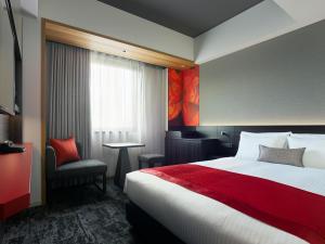 a hotel room with a large bed and a chair at Mitsui Garden Hotel Ginza-gochome in Tokyo
